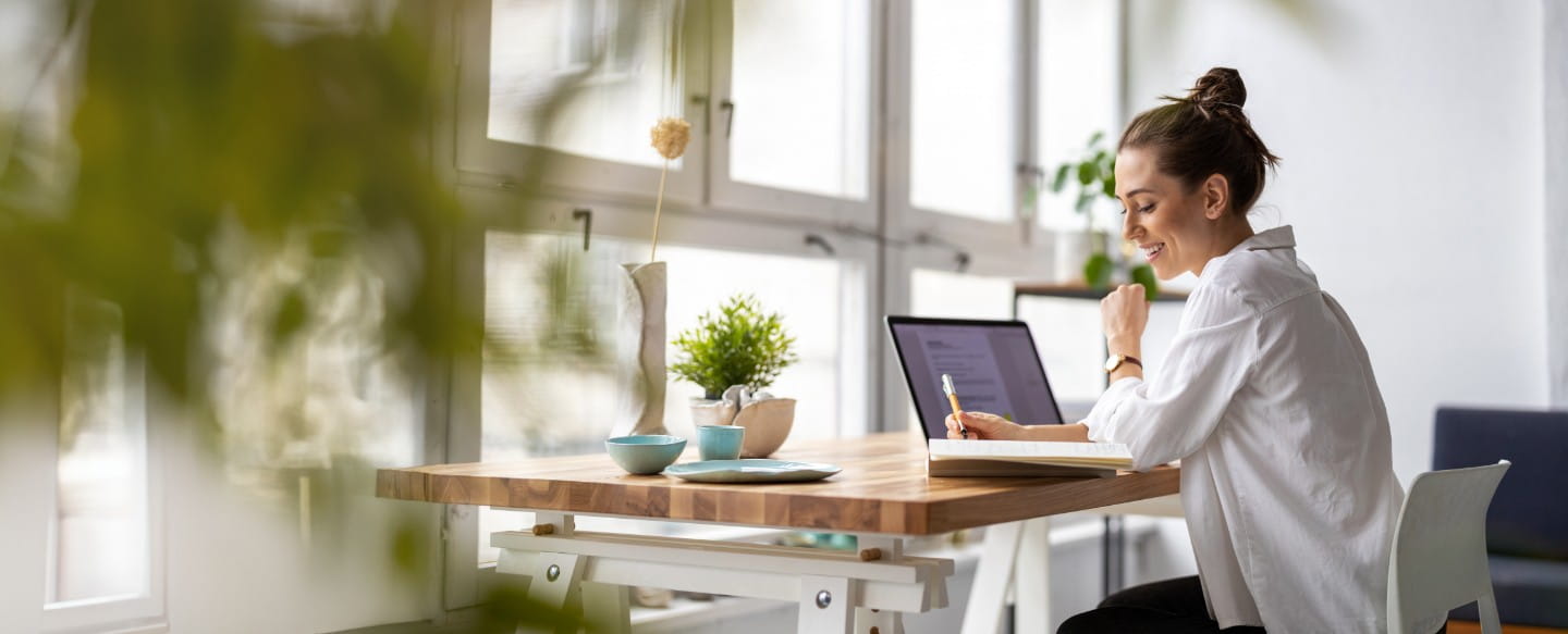 Frau sitzend am Schreibtisch mit Laptop