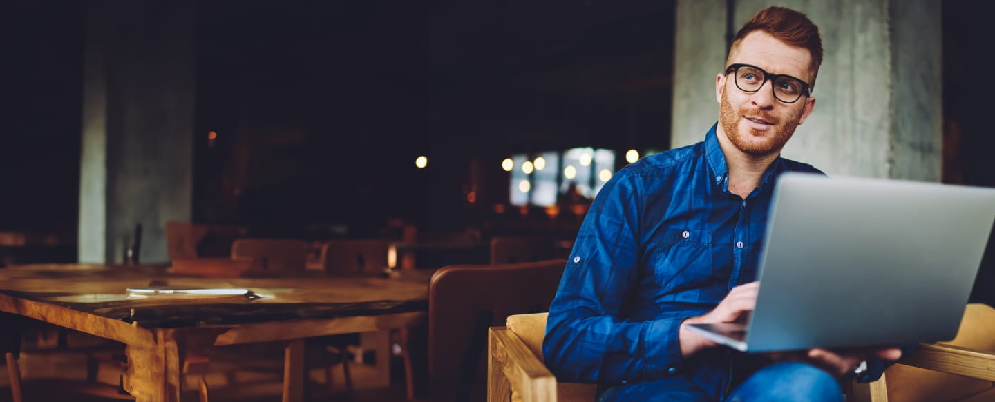Mann mit Laptop im Sessel sitzend