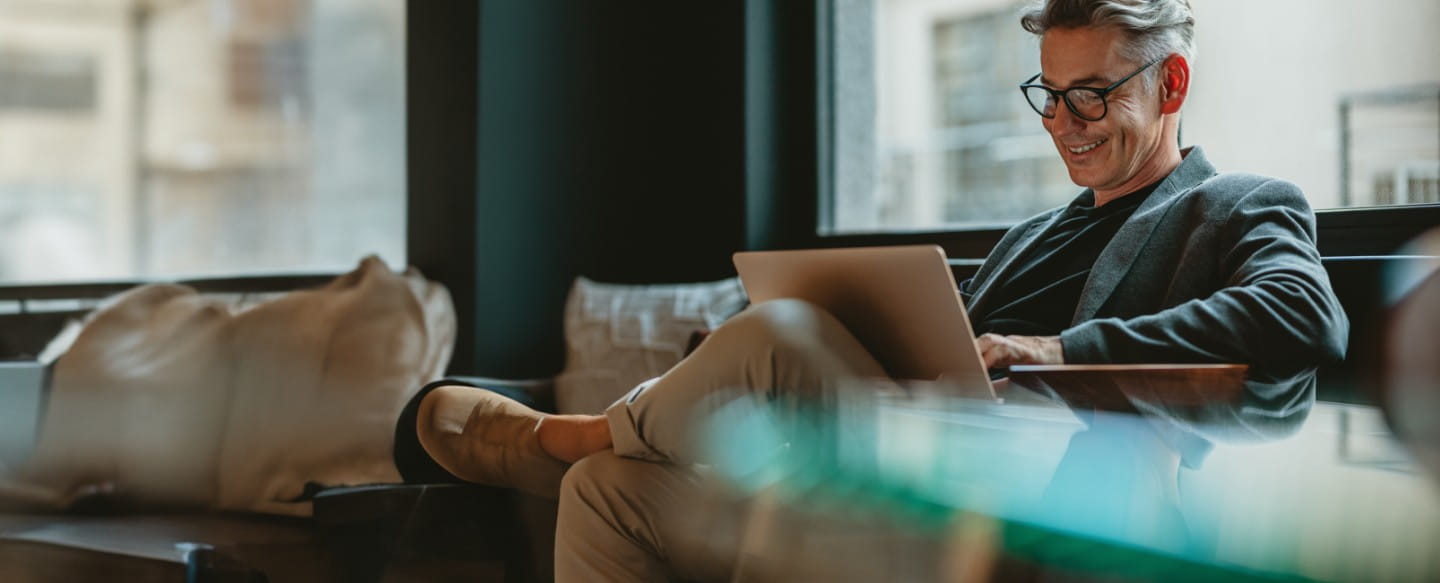 Mann auf Sofa am Laptop arbeitend